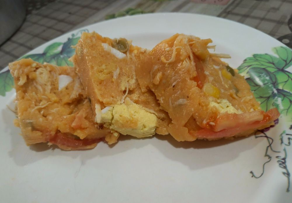foto de cuscuz paulista de frango desfiado com pedaços de tomate, ovo cozido, milho e ervilha 
