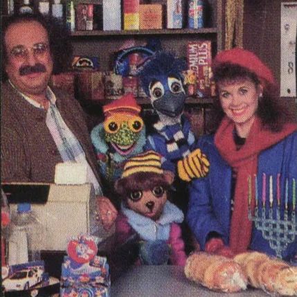 Holly Larocque and the puppet cast of “Under the Umbrella Tree” with guest Harvey Atkin as Mr. Goldberg, a store owner and former magician, in a Hanukkah special.