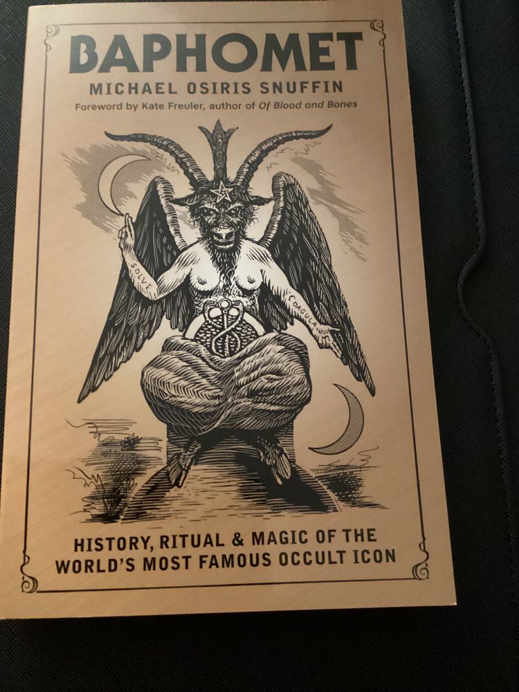 The cover of Baphomet: History, Ritual, and Magic of the World’s Most Famous Occult Icon by Michael Osiris Snuffin. The figure of a goat headed being with goat legs and human breasts sits in the middle of the cover. There is a crescent moon to their upper right and lower left, and a pentacle is drawn on their forehead.