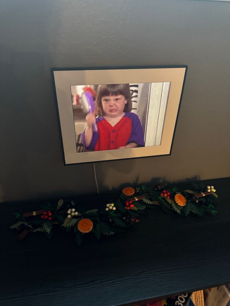 Digital picture frame on wall featuring angry little girl with hairbrush