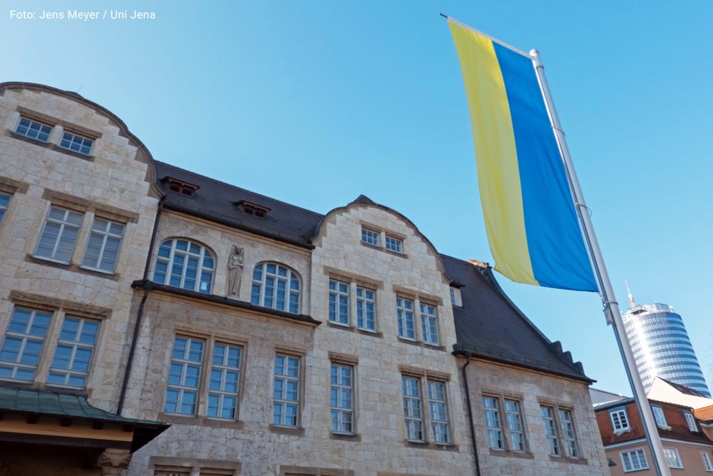 Eine ukrainische Flagge vor dem Jenaer Universitätshauptgebäude. Foto: Jens Meyer / Uni Jena