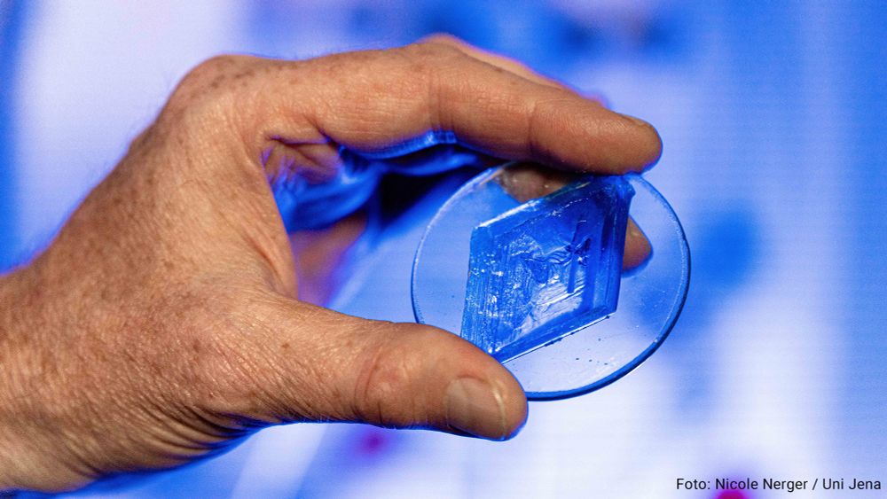 A hand presents the crystal of a copper compound used by the team led by Prof. Dr Winfried Plass to investigate spin states in molecules.