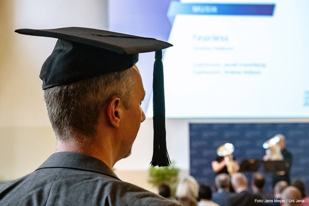 Eine Person trägt einen Doktorhut während des Festaktes am Schillertag an der Uni Jena. Foto: Jens Meyer / Uni Jena
