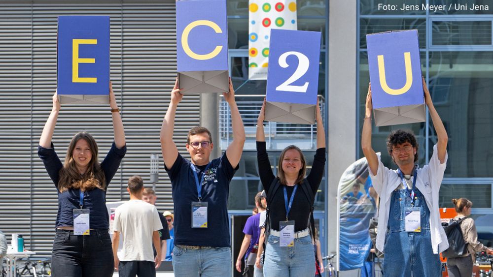 Vier Personen halten am Campus der Universität Jena die Buchstaben "EC2U" hoch. Foto: Jens Meyer / Uni Jena
