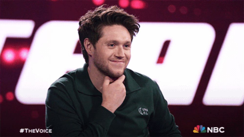 a man in a green shirt is smiling in front of a large nbc logo