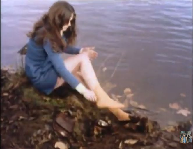 La chica ha tropezado y se ha mojado los zapatos, se ha sentado a quitarse las medias.