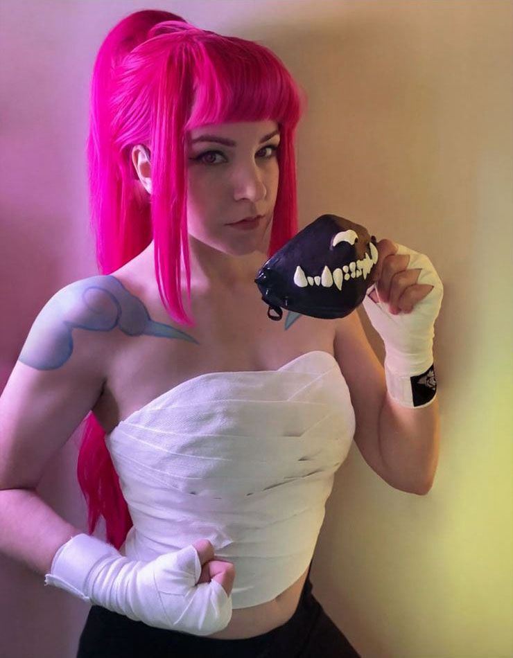 Fighter with pink hair holding up a mask shaped like wolf teeth