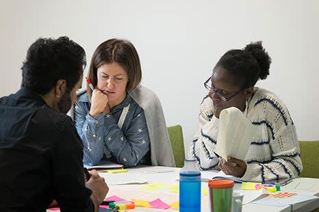 Delegates at the ALDinHE conference, working together around a table in a workshop. There are coloured sticky notes & paper.