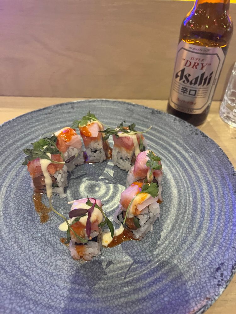 Circle of sushi pieces in a blue plate of a sushi roll called ‘Portal Passage’ 