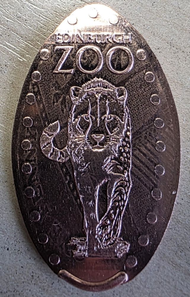 A pressed penny with a picture of a cheetah walking towards the viewer. Obtained at Edinburgh zoo. The penny is from the UK so part of the UK coat of arms can be seen stretched across the background of the penny.