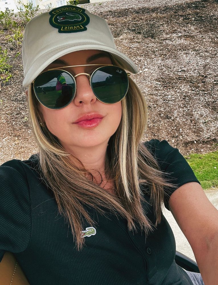 Me in a black bolo, aviator sunglasses and a white baseball hat in a golf cart 