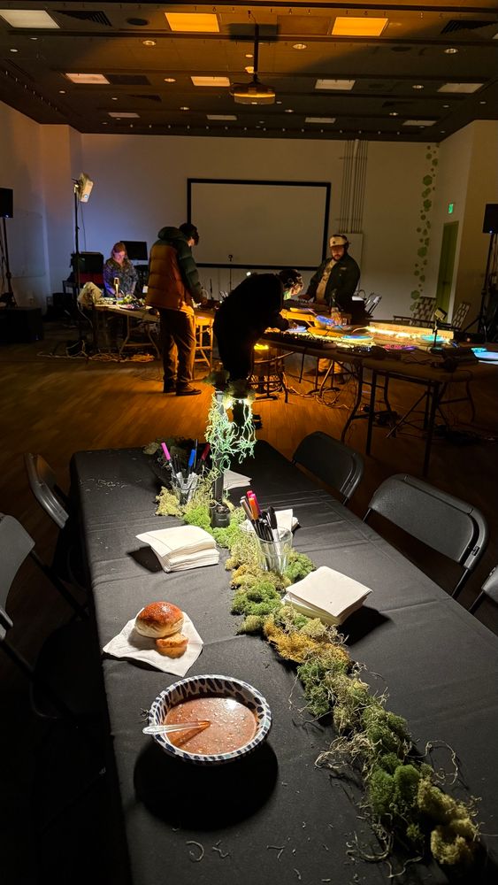 A bowl of soup in the foreground and people playing synthesizers in the background. 