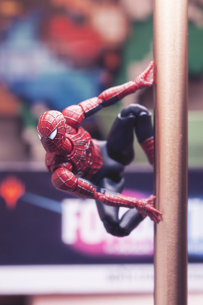 Photo d’une figurine de Spider-Man, accroché au pied d’une lampe.