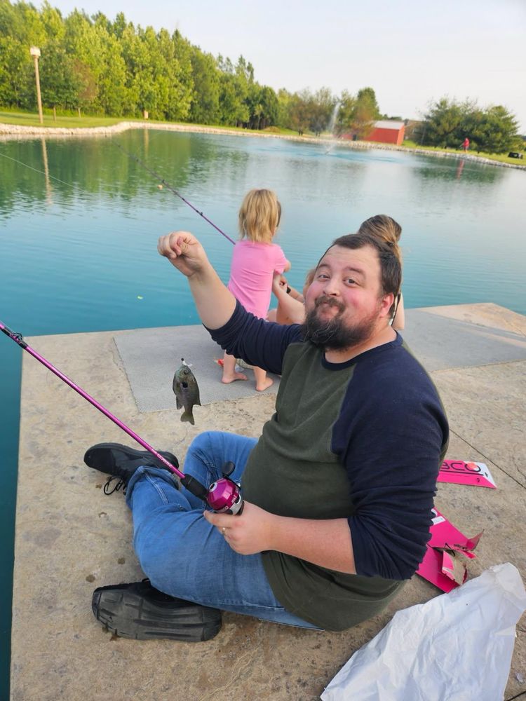 It's my white, middle-aged ass holding a pink fishing pole and a puny lil fish. You can see the back of my kid's heads in the background. 