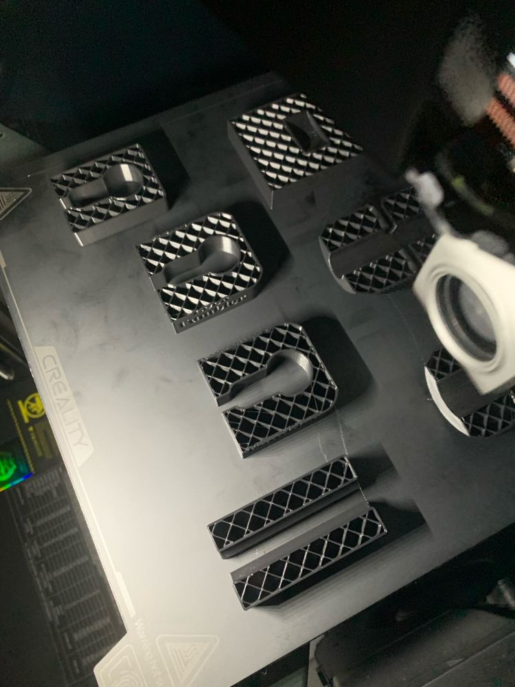 A Creality K1C printer starting to print some locksport bits and pieces. The sparse infill pattern (15%) is clearly visible inside the partially printed pieces. 