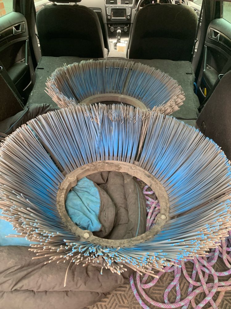 The back of an estate car, containing two brush heads taken from street sweeper machines. Both used. The steel bristles are to be recycled to make lock picking tools. 