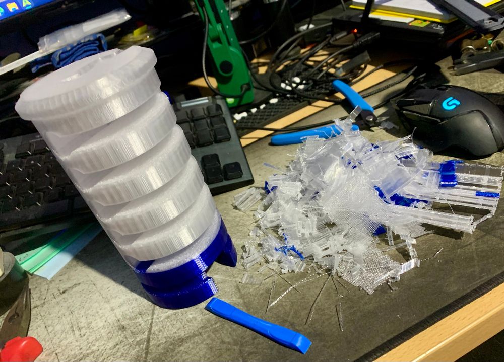 Another oversized 3D printed cutaway lock part, next to a pile of bridging material I’d just removed on a messy desk. 