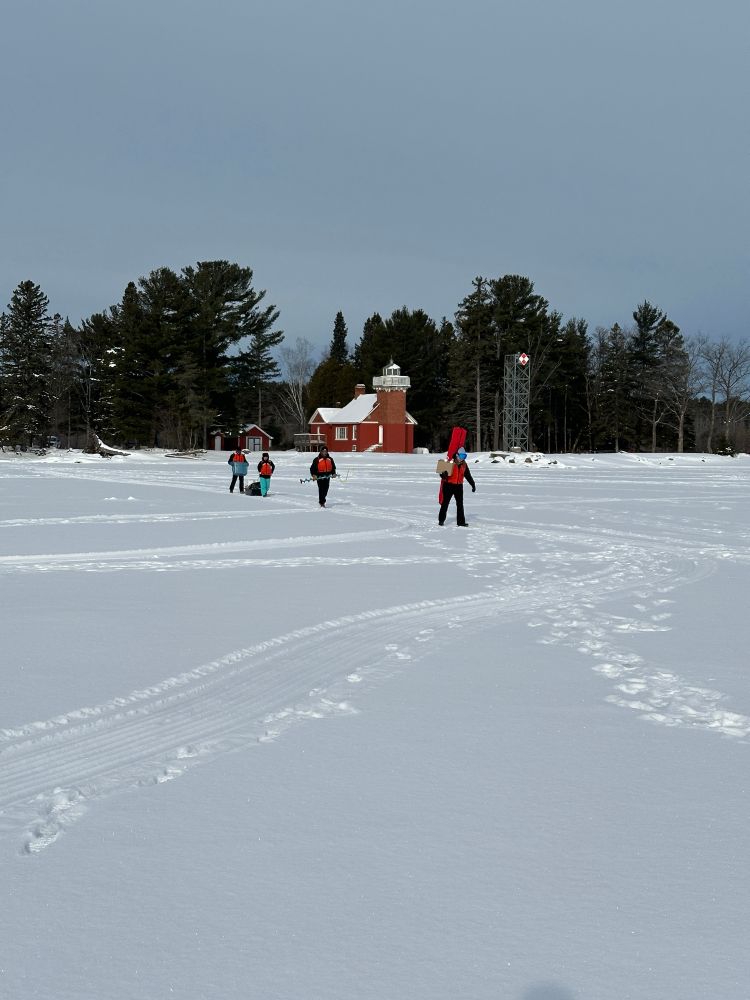 The field team carrying gear onto the lake ice.