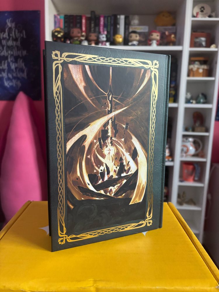 The back cover of the book is also green and features an illustration presumably of a scene from the book. The scene itself appears to show some kind of magical explosion and is bordered by a gold foil pattern.