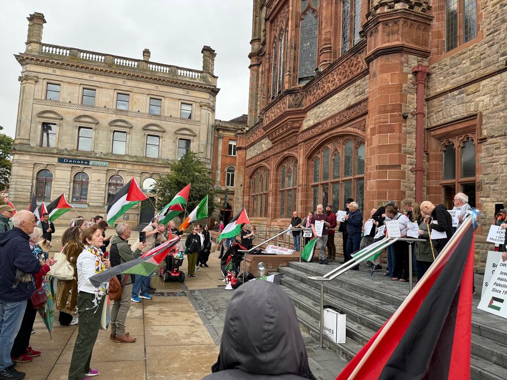 ‘Defend the Right to Protest’ rally in Derry’s Guildhall Square. There are people standing with 🇵🇸 flags and also a small number of 🇮🇪 flags.