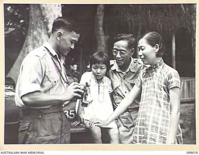 Man showing a camera to another man, woman and child