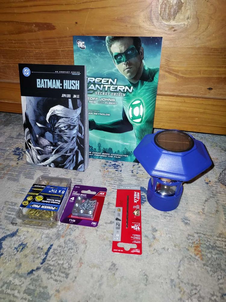 A DC Essentials copy of Batman Hush, and a movie tie-in cover for Secret Origin, a few screws and tools for the little free Library's assembly. And the unlit lantern for it.
