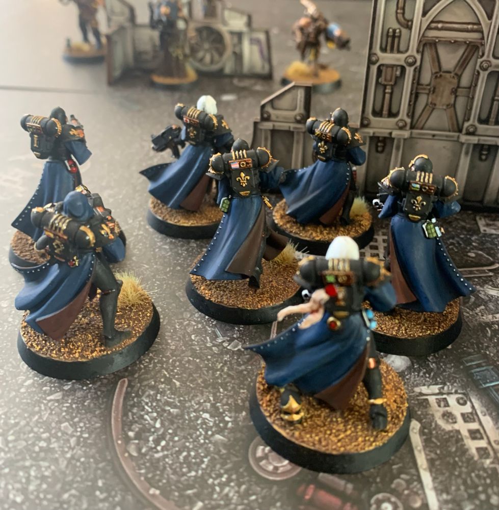 A painted Adepta Sororitas squad with backpack detail visible.