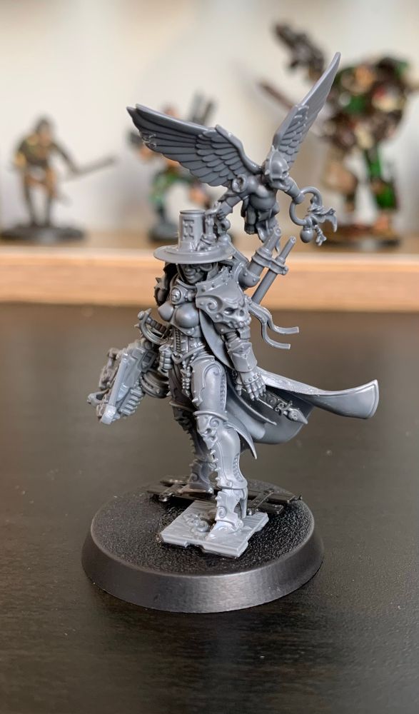 An unpainted Inquisitor miniature for Warhammer 40k, based on Inquisitor Greyfax, with base decoration and an attached cherub servitor.