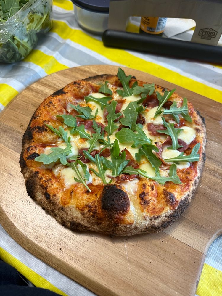 A prosciutto and bocconcini pizza finished with fresh arugula!
