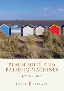 Picture shows the cover of Beach Hut and Bathing Machine by Kathryn Ferry, the rear view of beach huts looking out to sea.