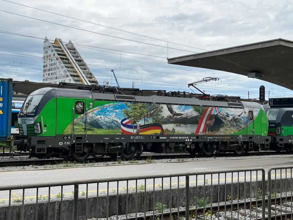 Electric multi-system locomotive "Vectron" in the station of Ljbljana with advertising stickers and the flags of the Netherlands, Germany and Austria.