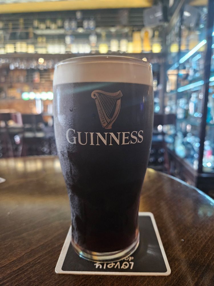 A pint of guinness on a beer mat on a wooden table.