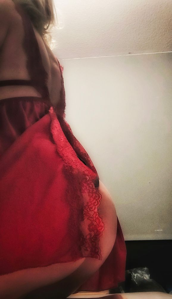 Lady Peri assise et photographiée de dos. Portant une nuisette rouge, fendue a l'arrière 