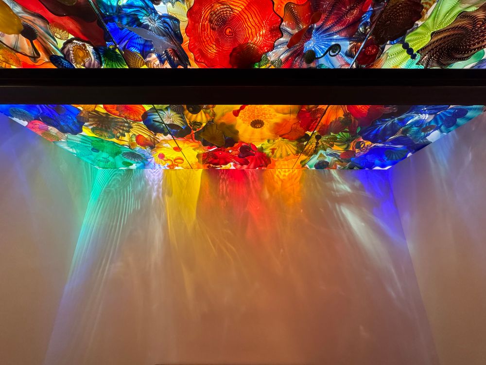 Ceiling covered in multicolored glass shapes. With light from above, the room looks like you’re inside of a kaleidoscope.