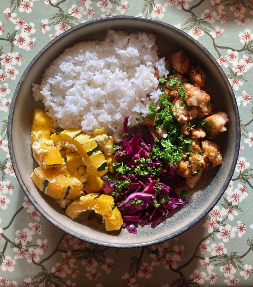 Photo d’une large assiette creuse avec du riz, du tofu croustillant, du chou rouge avec du persil, et de la courge avec de la feta.