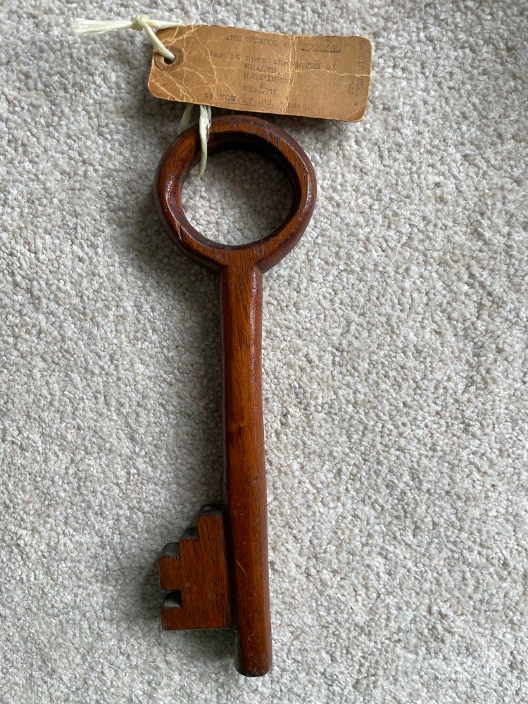 A large whittled wooden key with an old type-written tag 