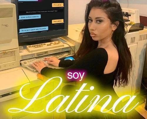Kali Uchis sitting by the computer with the caption in neon that says Soy Latina