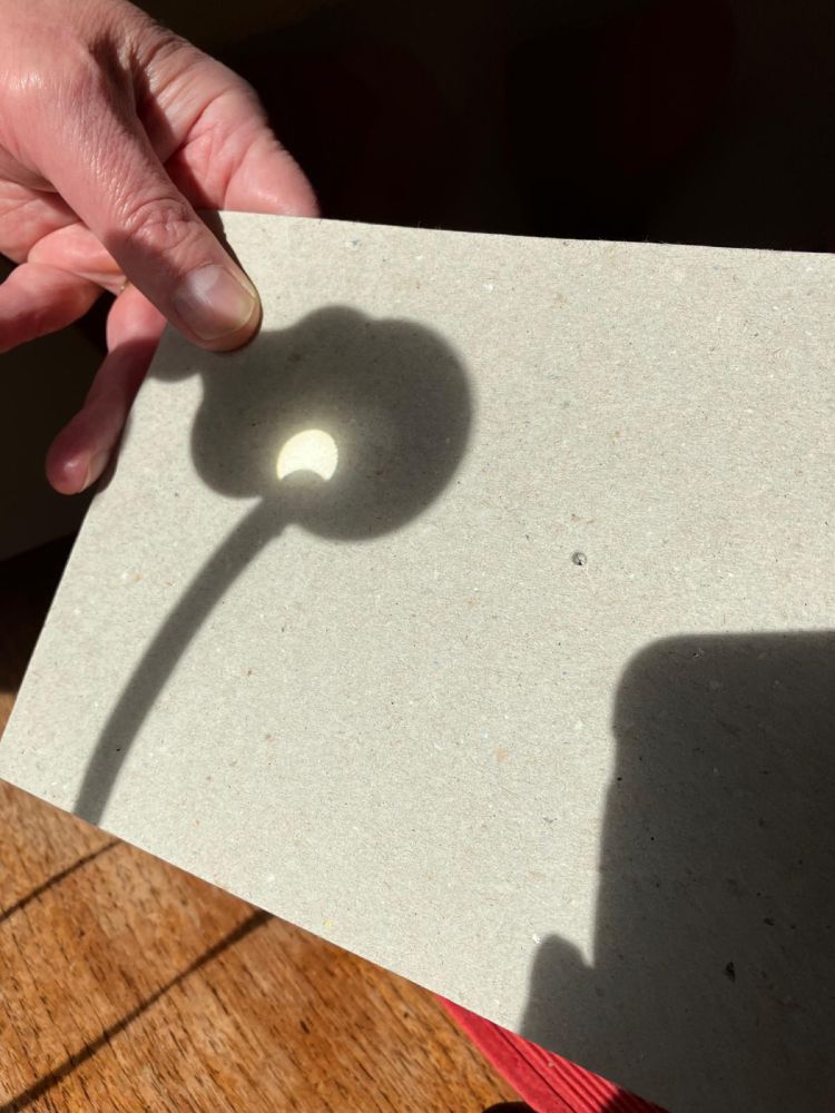 An image of a partially eclipsed sun, magnified and projected through one side of a pair of binoculars