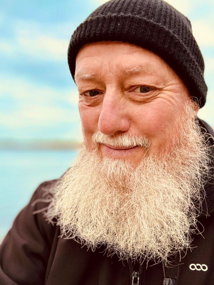 Alter weißer Mann mit Bart und Mütze. Im Hintergrund: Lake DingenKirchen
