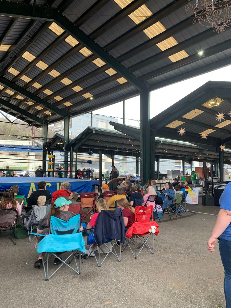 Outdoor area with awnings, a crowd of people and a wrestling ring. 