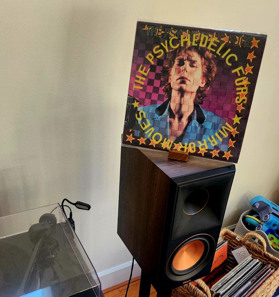 A copy of the album atop a speaker.  A basket of albums sits to the right and a turntable sits to the left. 