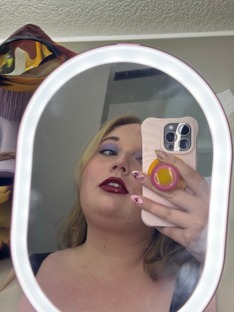 me a fat white woman in purple eyeshadow and glossy red lipstick taking a mirror selfie
