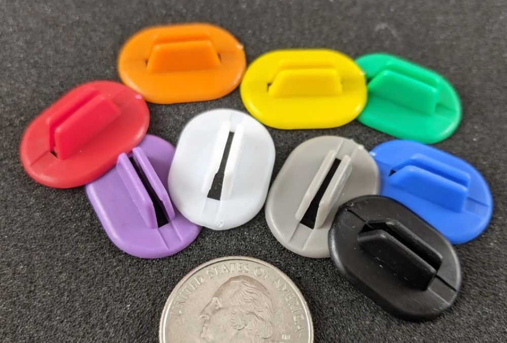 A collection of standees of various colors. A US quarter is shown for scale. 