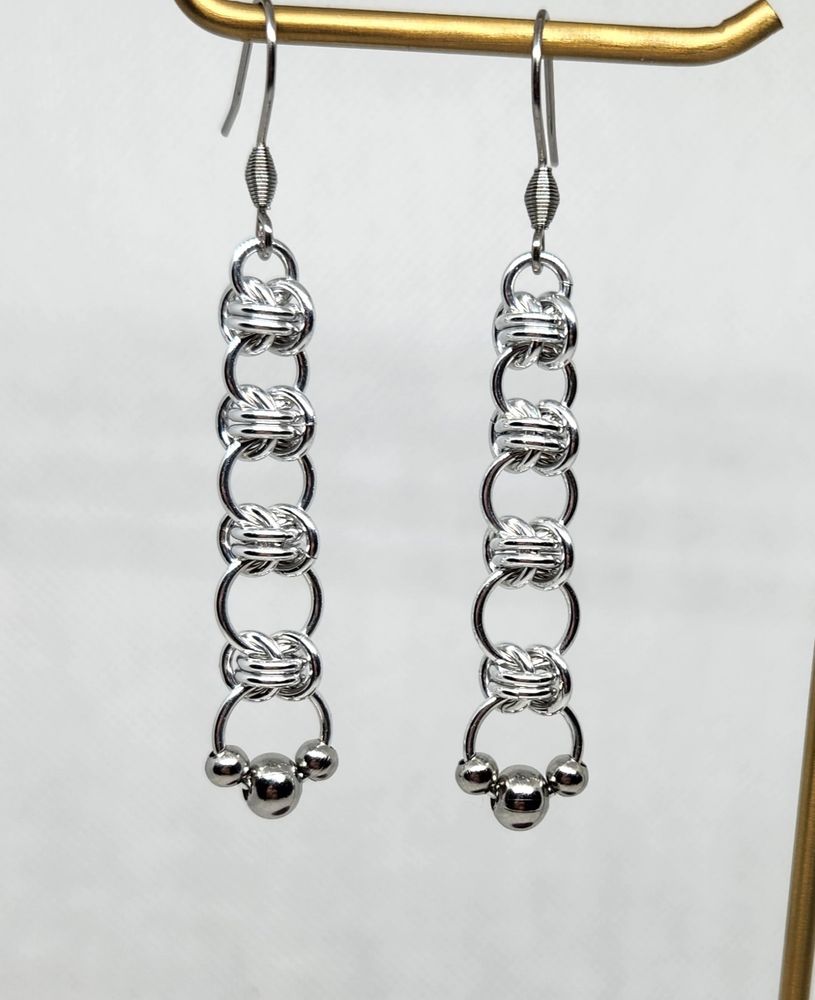 Earrings made of aluminium rings from small to extra large, with 3 steel beads on the largest ring at the bottom.