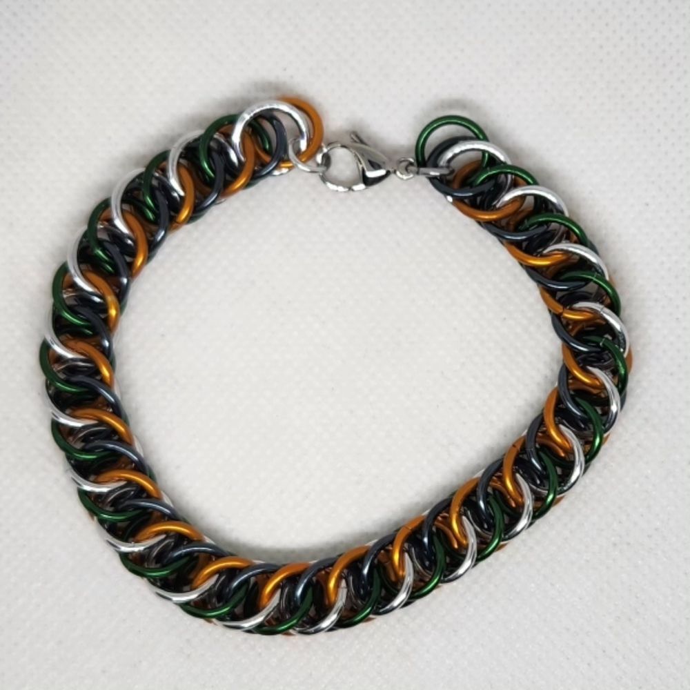 Chainmail bracelet in half Persian 4 in 1 weave, alternating green and silver on one side, orange and black on the other