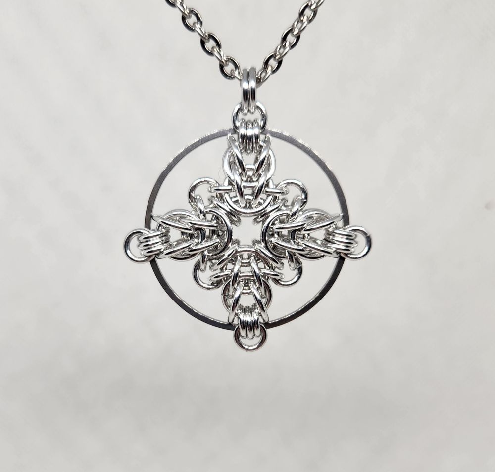 Silver chainmail cross within a larger circle
