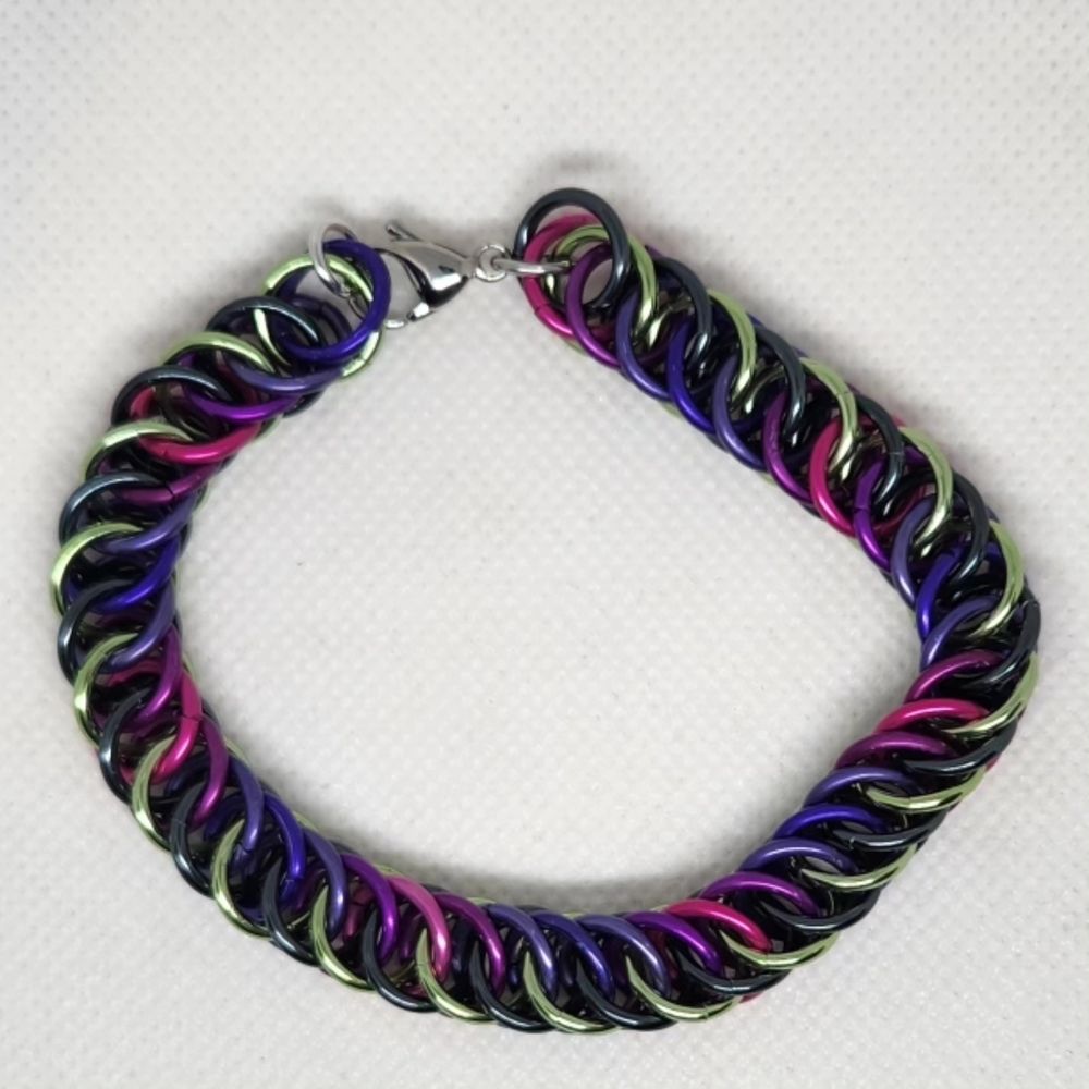 Chainmail bracelet in half Persian 4 in 1 weave, alternating green and black on one side and a gradient of pinks and purples on the other