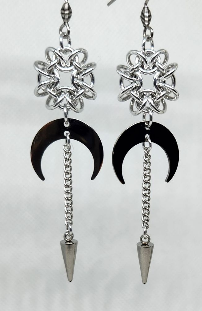 Silver earrings with round chainmail unit at the top, moons, and chains ending in spikes.
