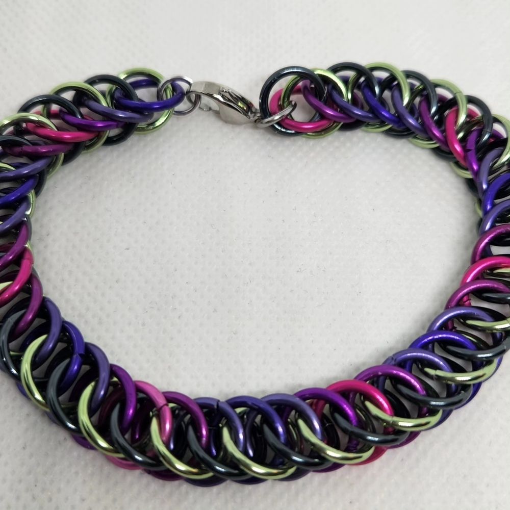 Chainmail bracelet in half Persian 4 in 1 weave, alternating green and black on one side and a gradient of pinks and purples on the other