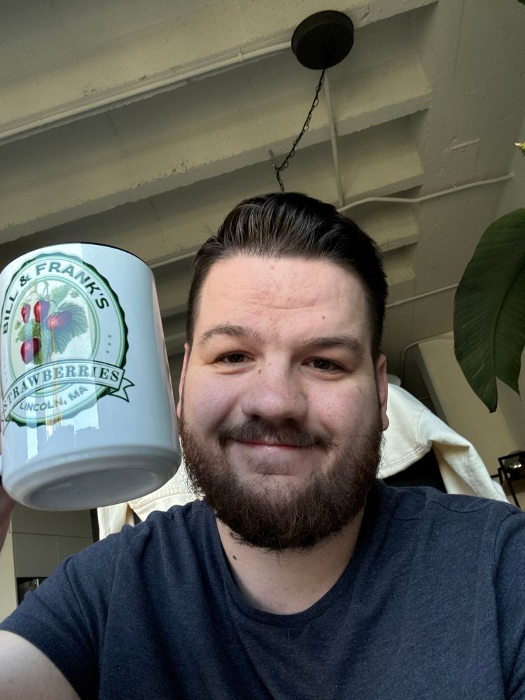 Selfie of me holding up a coffee cup that’s says “Bill and Frank’s Strawberries”